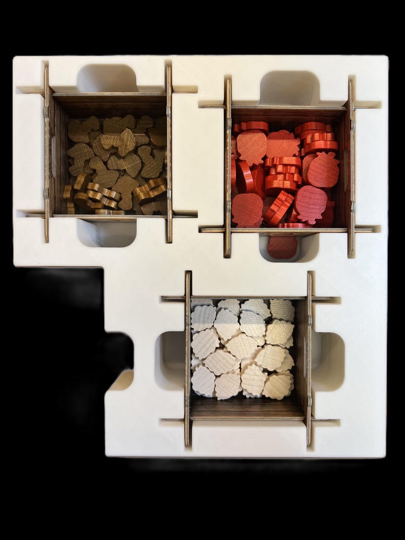 May include: A white foam insert with three compartments for storing game pieces. The compartments are filled with brown, red, and white wooden pieces.