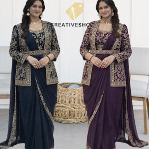 May include: Two women modelling saris. One is navy blue, the other is purple. Both saris feature detailed gold embroidery on the jacket, belt, and borders. The jackets have long sleeves and a matching belt. The text "CREATIVESHO" is visible.
