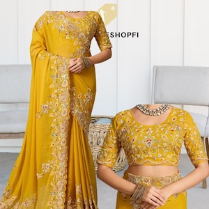 Puede incluir: Sari amarillo mostaza con intrincados bordados florales en el borde y el corpiño. El sari presenta una blusa a juego con bordados similares. El diseño incluye detalles dorados, rojos y verdes.