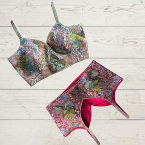 Könnte beinhalten: Zwei bestickte Stoffteile für ein traditionelles indisches Brautkleid. Das obere Teil ist weiß mit bunter Blumen Stickerei und das untere Teil ist rosa mit ähnlicher Stickerei.