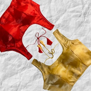 Könnte beinhalten: Zwei Seidenblusen, eine rote und eine goldene, mit einem Schnürrücken.