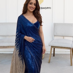 Peut inclure: Une femme porte un sari bleu foncé à paillettes avec un décolleté plongeant. Le sari présente un effet ombré or et bleu. Le texte "ESHOPFI" est visible en arrière-plan.