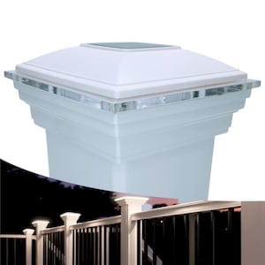 Puede incluir: Un foco de poste solar blanco con una lente de acrílico transparente. La luz está montada en un poste de valla blanco. La luz está encendida e ilumina la valla.