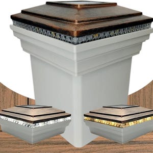 Puede incluir: Tapa de poste blanca con una parte superior de color bronce y una banda de pequeñas luces. Se muestran dos tapas de poste adicionales, una con detalles plateados y otra con detalles dorados. Las tapas son cuadradas y están diseñadas para uso en exteriores.