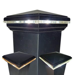 May include: Black post cap with a square top and a decorative trim. The cap has a clear, illuminated band around the top. Two additional caps with gold and silver trim are also shown.