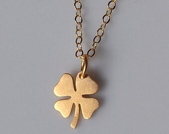 May include: A gold chain necklace with a four-leaf clover pendant.