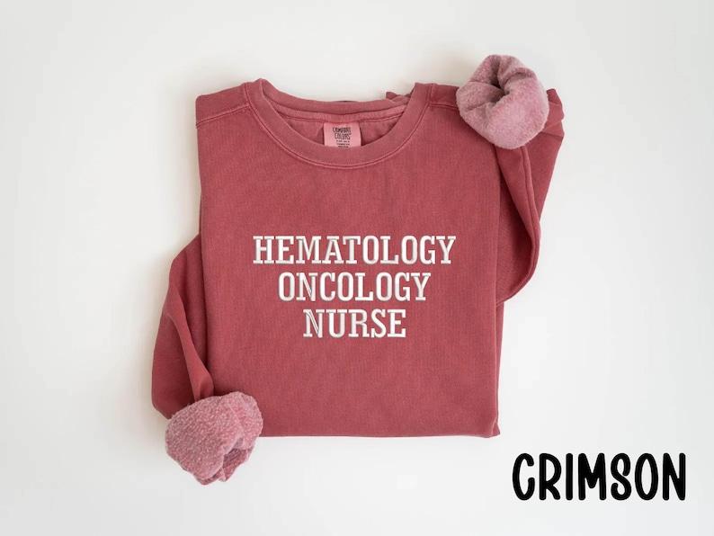 May include: Crimson red sweatshirt with the text "Hematology Oncology Nurse" in white.