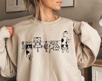 Sudadera con diseño de gatos colgados en la colada, un acogedor diseño para el hogar de los gatos.