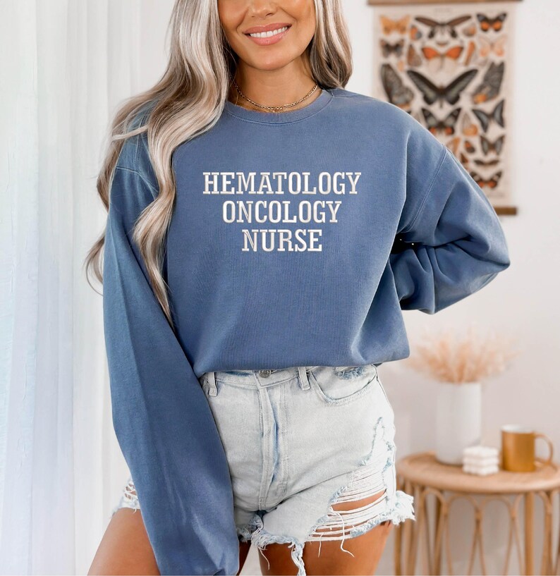 May include: A blue sweatshirt with the text "Hematology Oncology Nurse" in white lettering.