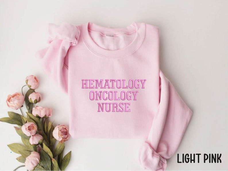May include: Light pink sweatshirt with the text "Hematology Oncology Nurse" in pink.