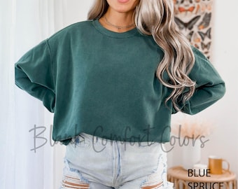 May include: A dark green, oversized sweatshirt with a crew neck. The sweatshirt is made of a soft, comfortable fabric and has a relaxed fit. The model is wearing the sweatshirt with a pair of light blue denim shorts.