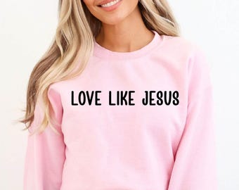 May include: Pink sweatshirt with the text "LOVE LIKE JESUS" in black.
