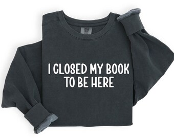 May include: Dark gray sweatshirt with the text "I closed my book to be here" printed in white.
