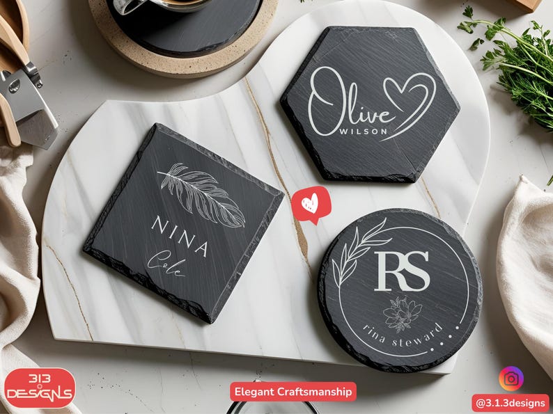 May include: A collection of personalized slate coasters in various shapes: square, hexagon, and round. Each coaster features custom white text and designs, including names, initials, and botanical elements. The coasters are arranged on a marble serving board.