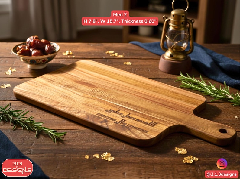 Puede incluir: Tabla de cortar rectangular de madera con asa, de 19,8 cm de alto y 39,9 cm de ancho. La tabla tiene texto grabado y est&aacute; rodeada de elementos decorativos, incluyendo un peque&ntilde;o cuenco de d&aacute;tiles y una linterna vintage.