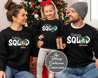 May include: Black Christmas Squad sweatshirts with Mickey Mouse graphics. The sweatshirts have the text "Christmas Squad" and personalized names. A family poses in front of a Christmas tree, with a gift box.