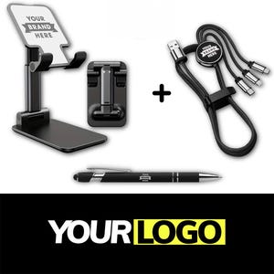 May include: A black phone stand, a black charging cable with multiple connectors, and a black pen are displayed. The phone stand and charging cable have space for a brand logo. The pen has a silver accent and a brand logo.