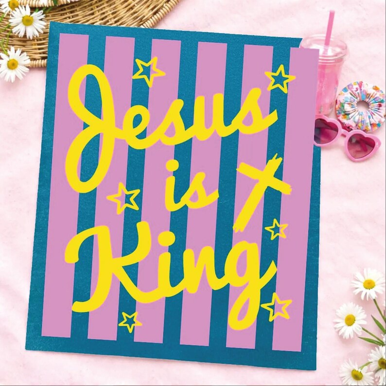 A colorful sign with the text "Jesus is King" in yellow and pink letters, surrounded by stars and flowers.