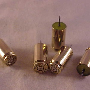May include: Five gold-colored bullet casings with a small pin protruding from the top. The casings are labeled "Federal 40 S&W" and "Win 40 S&W".
