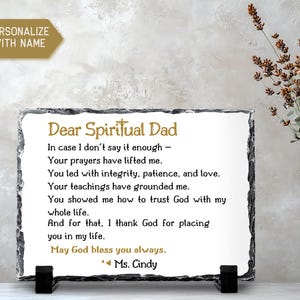 May include: A rectangular slate plaque with a white center and black border, featuring the text "Dear Spiritual Dad" and a heartfelt message. The plaque is supported by a black stand and is personalized with a name.