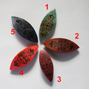 May include: Five wooden yarn bowl stitch holders in different colors and designs. The bowls are shaped like an oval and have a decorative pattern carved into the wood. The colors are teal, red, brown, maroon, and dark blue.