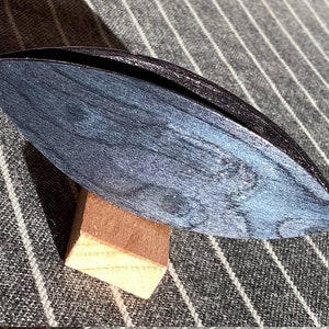 Op de afbeelding: Een donkerblauwe houten garenwinder met een natuurlijke houten basis. De winder is ontworpen om garen vast te houden voor breien of haken.