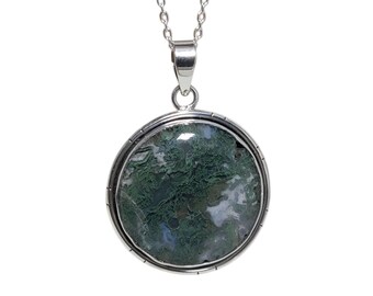 May include: A round pendant necklace featuring a moss agate stone with green and white patterns. The stone is set in a silver-colored metal frame and hangs from a delicate silver chain. The pendant is approximately 1.5 inches in diameter.