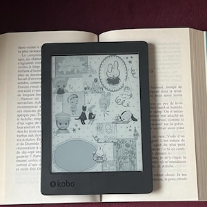 May include: A black Kobo e-reader displaying a colorful cartoon illustration of a bunny and other characters. The e-reader is open on a book with text. The Kobo logo is visible.