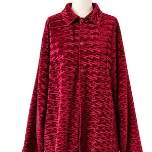 May include: A long-sleeved button-down shirt in a deep red velvet fabric. The garment features a textured, wavy, or zig-zag pattern throughout the material. It includes a standard collar and a front placket with matching red buttons.