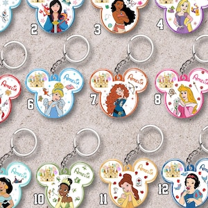 May include: Twelve Mickey-shaped keychains featuring various animated characters, a castle illustration, and the name Amelia printed in script. Each keychain includes a metal ring and chain, showcasing colorful designs of princesses and their companions.
