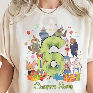 May include: A cream-colored t-shirt featuring a large green number six surrounded by various cartoon animal characters wearing party hats. The design includes colorful gift boxes, balloons, and the text Custom Name printed in green at the bottom.