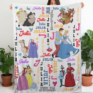 May include: A white blanket featuring illustrations of Cinderella characters and the name "Julia" in various fonts and colors. The blanket includes images of Cinderella, the Prince, and other characters from the movie.