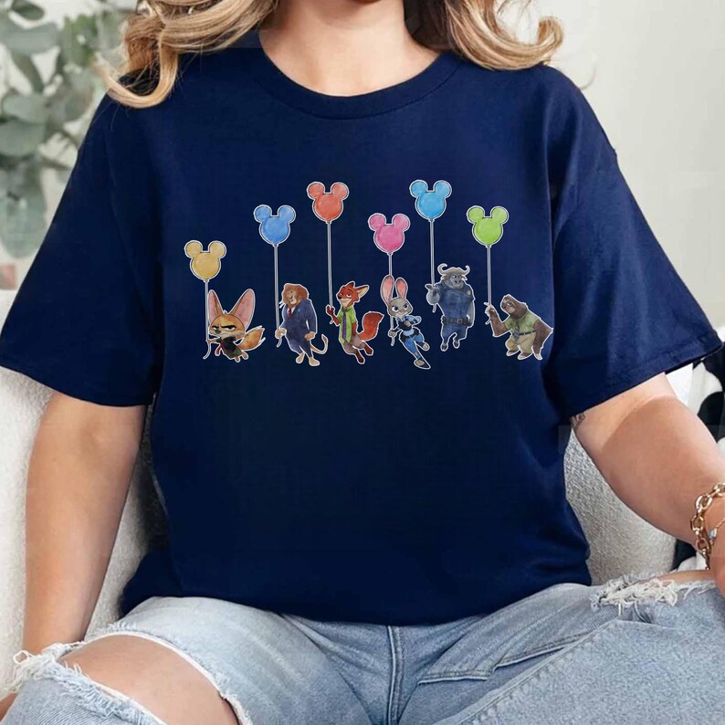 May include: Navy blue t-shirt featuring a colorful graphic of characters from a popular animated movie. The characters are holding balloons in various colors. The balloons have Mickey Mouse ears. The shirt is made of a soft material.