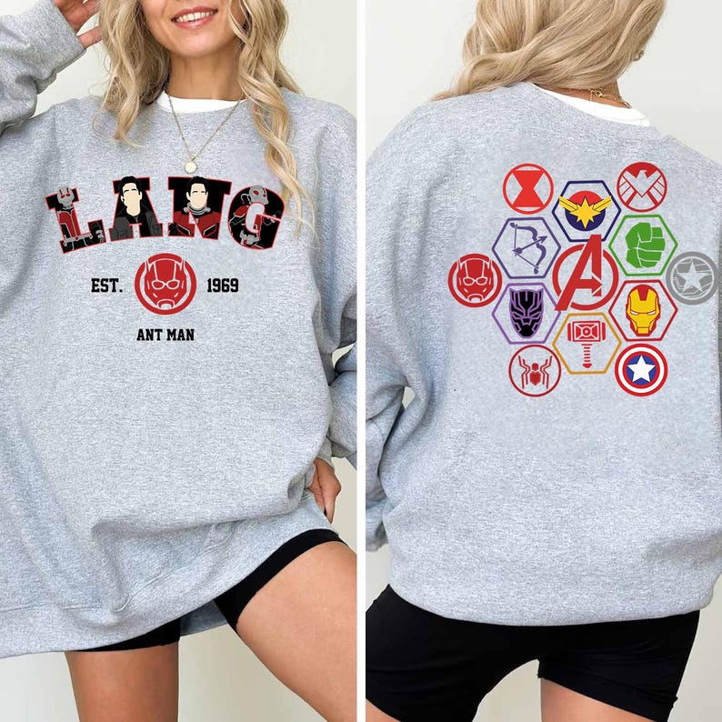 Puede incluir: Una sudadera gris claro con la palabra "LANG" en letras rojas y negras, con personajes de Ant-Man. La parte delantera tambi&eacute;n muestra "EST. 1969 ANT MAN". La parte trasera tiene un dise&ntilde;o colorido del logotipo de los Vengadores. La sudadera tiene cuello redondo blanco.
