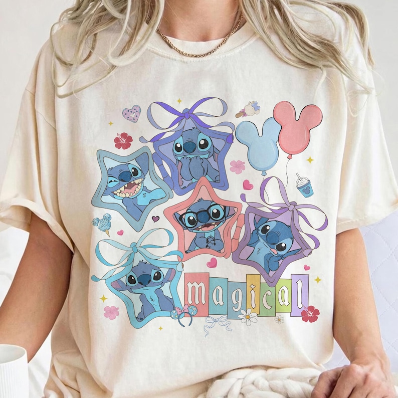 Może przedstawiać: Kremowa koszulka z kolorową grafiką postaci Stitch w ramkach w kształcie gwiazd z kokardkami, balonami i napisem "magical". Projekt zawiera r&oacute;żne wyrazy twarzy Stitch i pastelowe kolory.