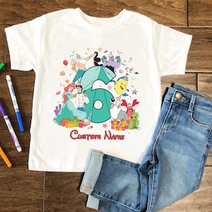 K&ouml;nnte beinhalten: Ein wei&szlig;es Kurzarm-T-Shirt mit einer gro&szlig;en t&uuml;rkisfarbenen Zahl sechs, umgeben von bunten Zeichentrickfiguren aus Arielle, die Meerjungfrau, darunter Arielle, Prinz Erik, Fabius, Sebastian, Triton und Ursula, mit dem Text Custom Name darunter.