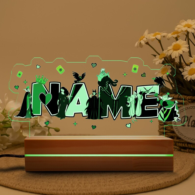 May include: A personalized night light featuring the word "NAME" in a green font, with cartoon villain characters. The light sits on a wooden base with a green illuminated stripe. The overall design is a decorative item.