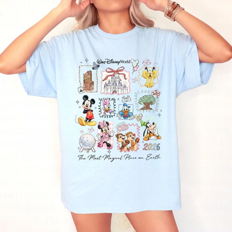 Puede incluir: Camiseta azul claro con un dise&ntilde;o colorido de Disney. El dise&ntilde;o incluye personajes como Mickey y Minnie Mouse, y lugares emblem&aacute;ticos. El texto dice "Walt Disney World", "2026" y "The Most Magical Place on Earth".