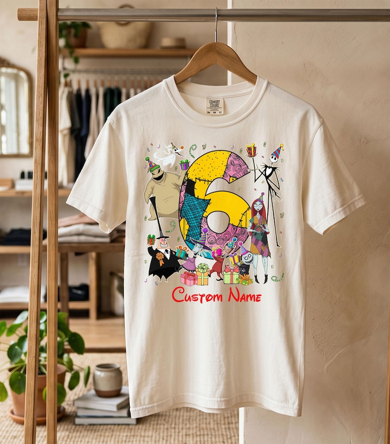 May include: A cream-colored short-sleeve t-shirt featuring a large yellow number six surrounded by various characters from The Nightmare Before Christmas, including Jack Skellington and Sally, with the red text Custom Name printed below.