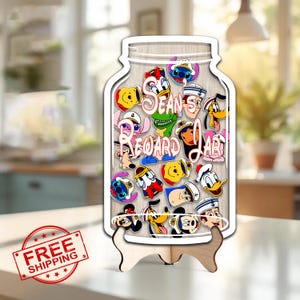 May include: A wooden jar-shaped display with various cartoon character pins. The jar has the words "Sean's Reward Jar" in cursive. The display is supported by a small wooden stand. The pins feature characters like Mickey Mouse, Donald Duck, and Stitch.
