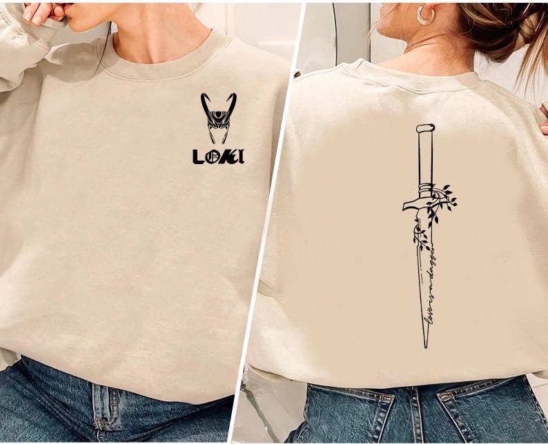 May include: Beige sweatshirt featuring a black graphic of Loki's helmet and the word "LOKI" on the front. The back displays a black dagger design with floral accents and the text "lovers & dagger".