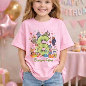 May include: A light pink short-sleeve t-shirt featuring a large green number six surrounded by various cartoon animal characters wearing party hats, colorful gift boxes, and the text Custom Name printed in green cursive lettering below.