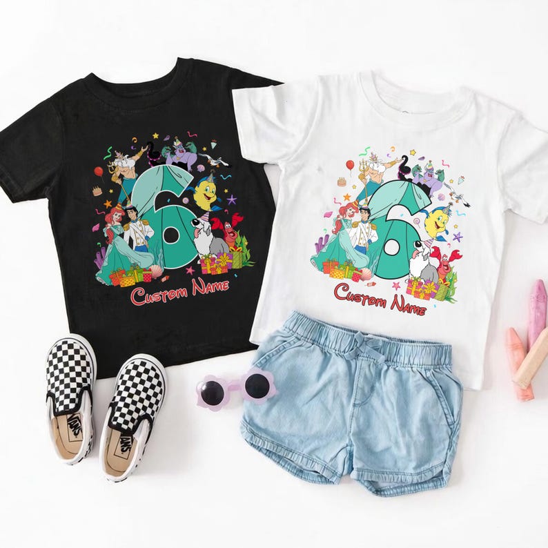 K&ouml;nnte beinhalten: Ein schwarzes T-Shirt und ein wei&szlig;es T-Shirt, jeweils mit einer gro&szlig;en t&uuml;rkisfarbenen Sechs, umgeben von bunten Zeichentrickfiguren, Partydekorationen und dem Text Custom Name. Dazu ein Paar schwarz-wei&szlig; karierte Slipper zum Hineinschl&uuml;pfen.