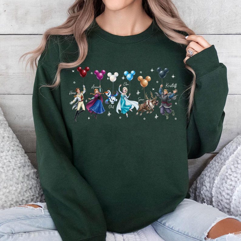 May include: Dark green sweatshirt featuring characters from a popular animated movie. The design includes illustrations of characters holding balloons with Mickey Mouse ears. Names of the characters are written above them.