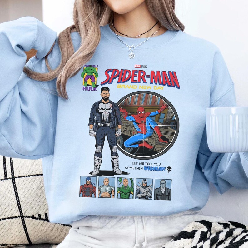 May include: Light blue sweatshirt featuring a comic book-style graphic of Spider-Man, The Punisher, and Hulk. The graphic includes the text "Spider-Man Brand New Day" and other comic book elements. The sweatshirt has a crew neck.
