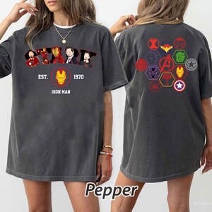 Puede incluir: Camiseta gris oscuro con la palabra "STARK" e ilustraciones de Iron Man, adem&aacute;s de "EST. 1970 IRON MAN". La parte trasera muestra logotipos de superh&eacute;roes en un patr&oacute;n hexagonal. La camiseta tiene un corte holgado y c&oacute;modo.