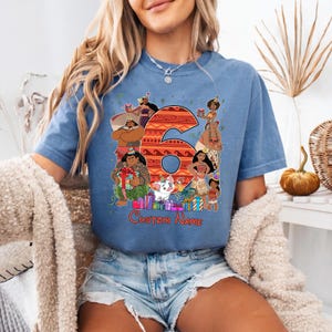 May include: A blue t-shirt featuring a large orange number 6 with a patterned design, surrounded by various animated characters wearing party hats, colorful gift boxes, and the text Custom Name printed in red at the bottom of the graphic.