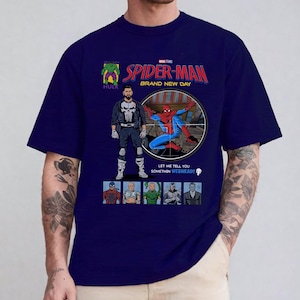 May include: Navy blue t-shirt featuring a comic book style graphic of Spider-Man, The Punisher, and other Marvel characters. The text "SPIDER-MAN BRAND NEW DAY" is displayed in red and yellow. The shirt has a crew neck and short sleeves.
