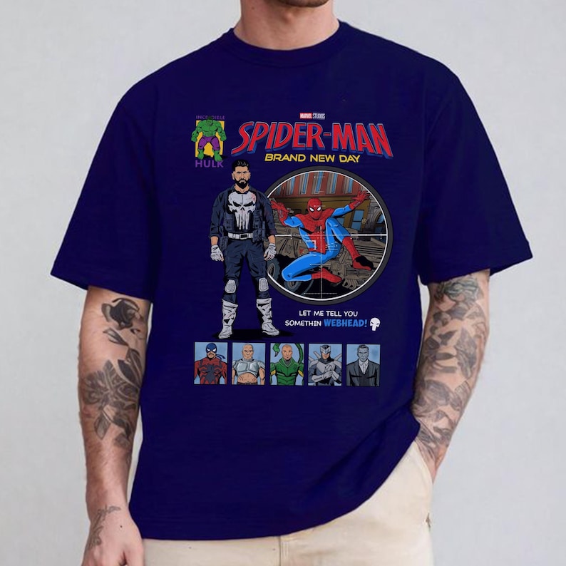 May include: Navy blue t-shirt featuring a comic book style graphic of Spider-Man, The Punisher, and other Marvel characters. The text "SPIDER-MAN BRAND NEW DAY" is displayed in red and yellow. The shirt has a crew neck and short sleeves.