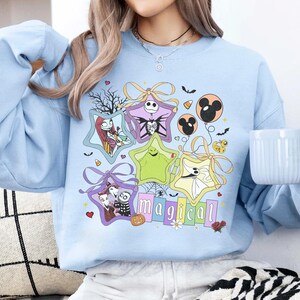 May include: A white ceramic mug with a black handle and the text "But First, Coffee" in a bold, black font. The mug is set against a blurred background, suggesting a cosy setting.